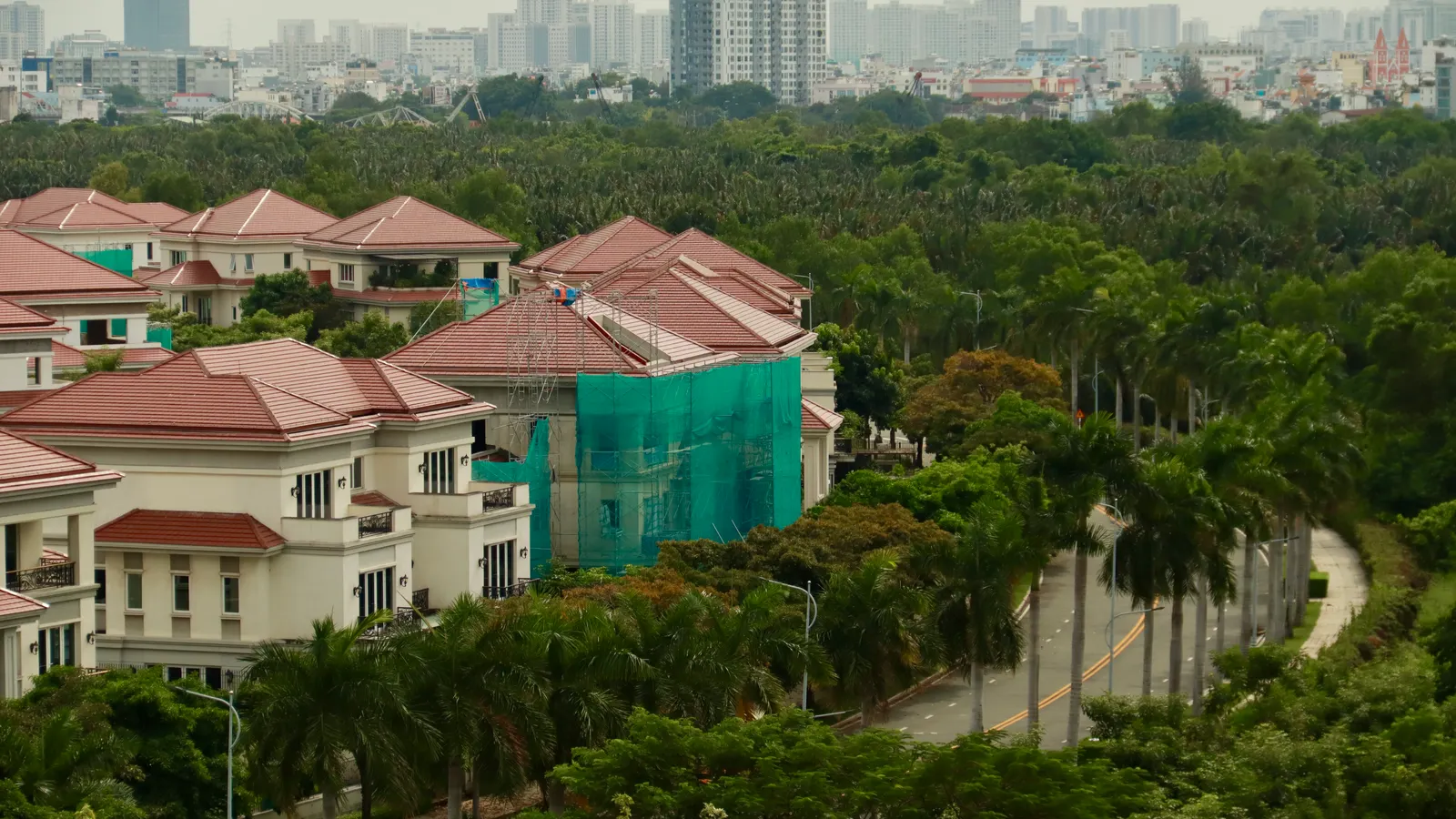 Deretan rumah beratap merah di antara pepohonan, dilihat dari atas